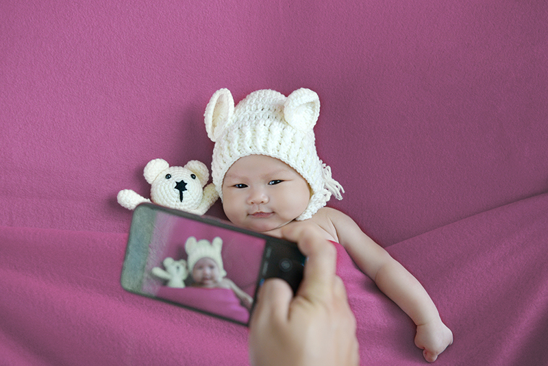 Mom taking newborn picture with her smartphone.