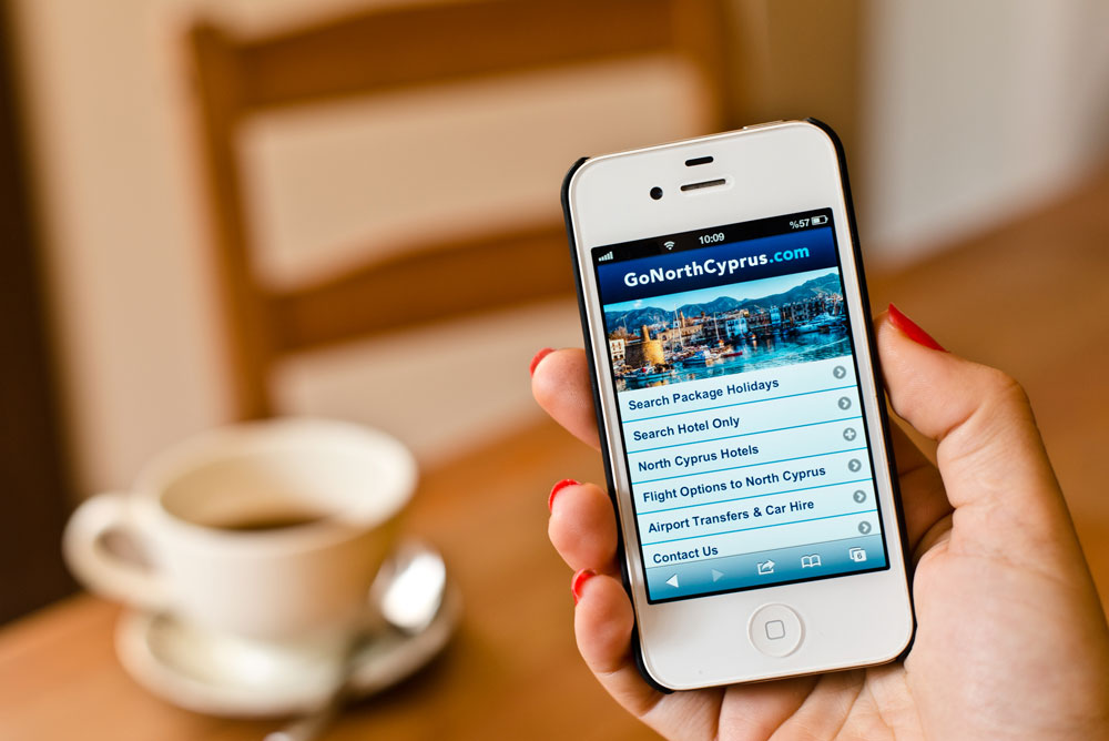 Holding an iPhone with Go North Cyprus mobile website open'